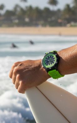 gul watches surfer with green watch powered by light , by beach
